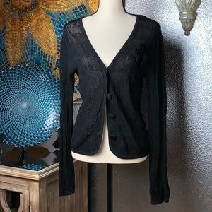 Black crochet cardigan sweater with rose accents.